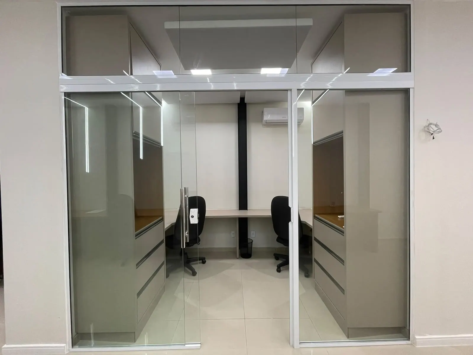 Sala privativa vista de fora, com porta de vidro, duas mesas, cadeiras e armários